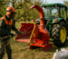 Tocator tractat într-o livadă pentru reciclare resturi tocate, operator în echipament de protecție