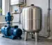 Vas de expansiune din inox montat lângă un hidrofor într-o cameră tehnică