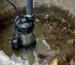 Pompă de apă murdară cu tocător într-un cămin cu apă tulbure și resturi organice
