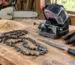 Aparat pentru ascuțirea lanțului de drujbă pe un banc de lucru, alături de lanț și accesorii de întreținere