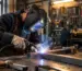 Sudor într-un atelier purtând o mască de sudură automată în timpul unei lucrări metalice